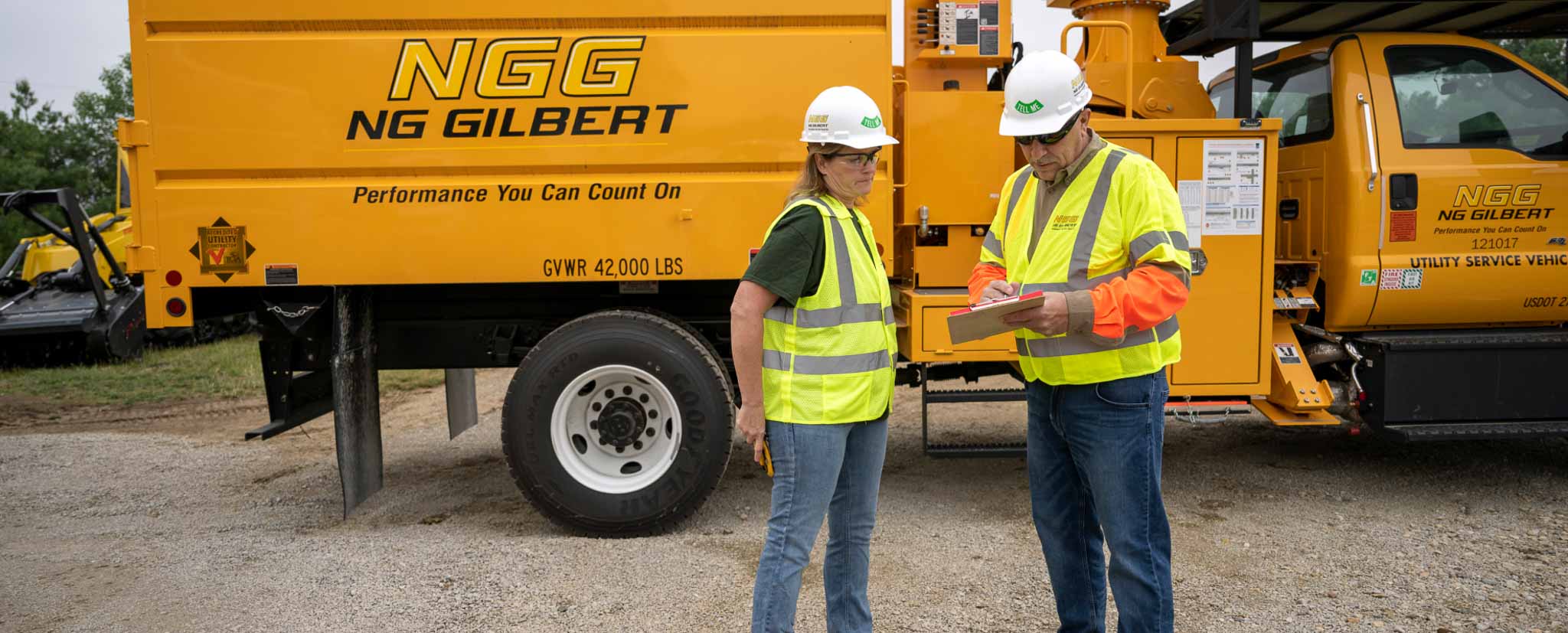 Two workers discussing something outside of a NG Gilbert branded truck