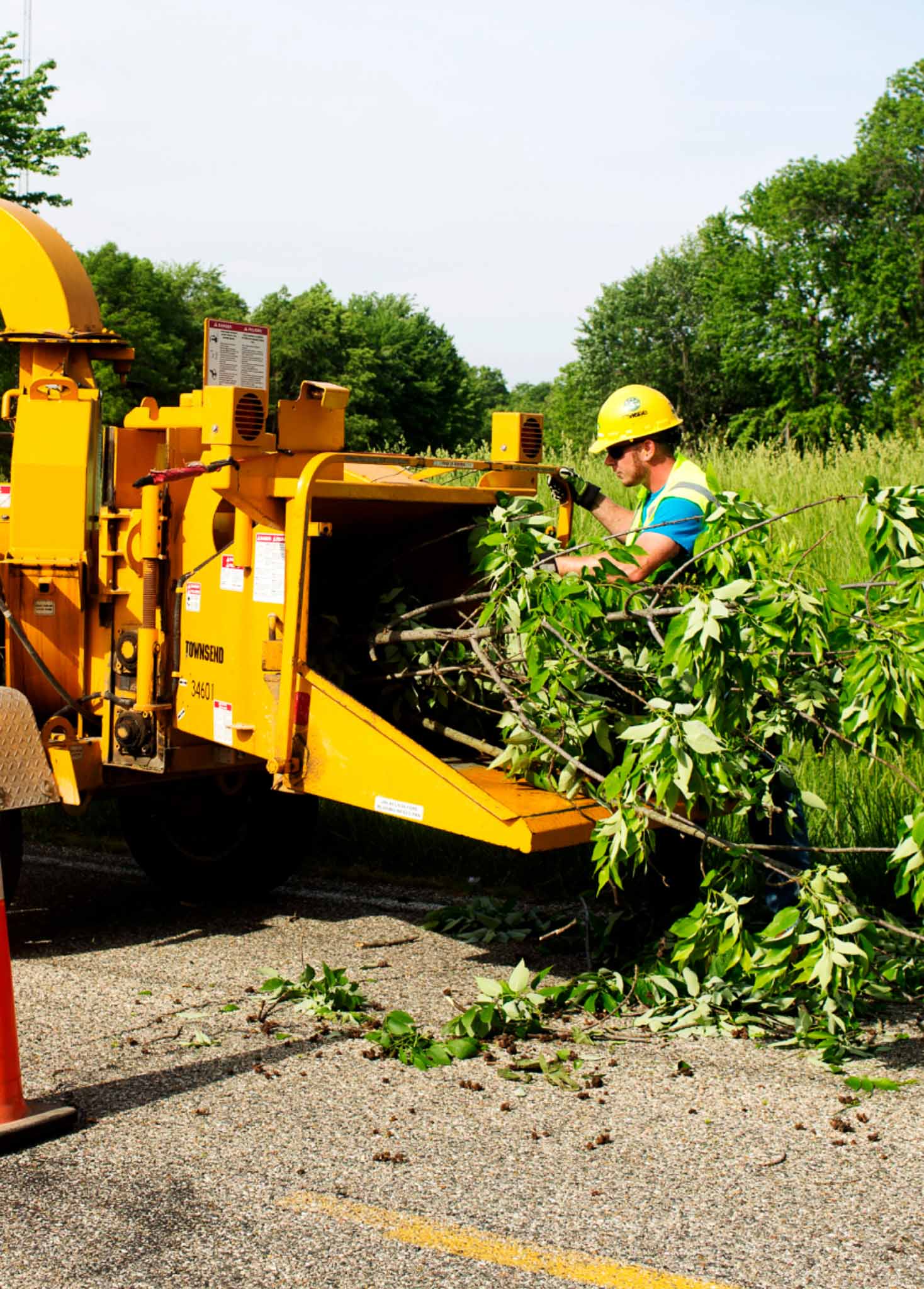 A worker feeding branches into a wood chipper