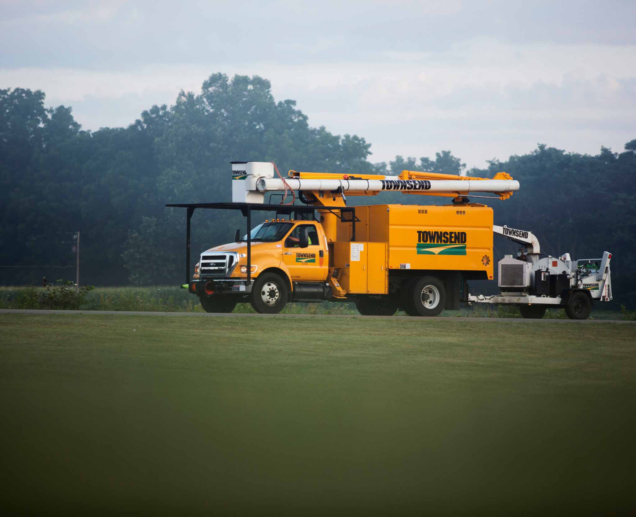 A cherry picker truck pulling a wood chipper