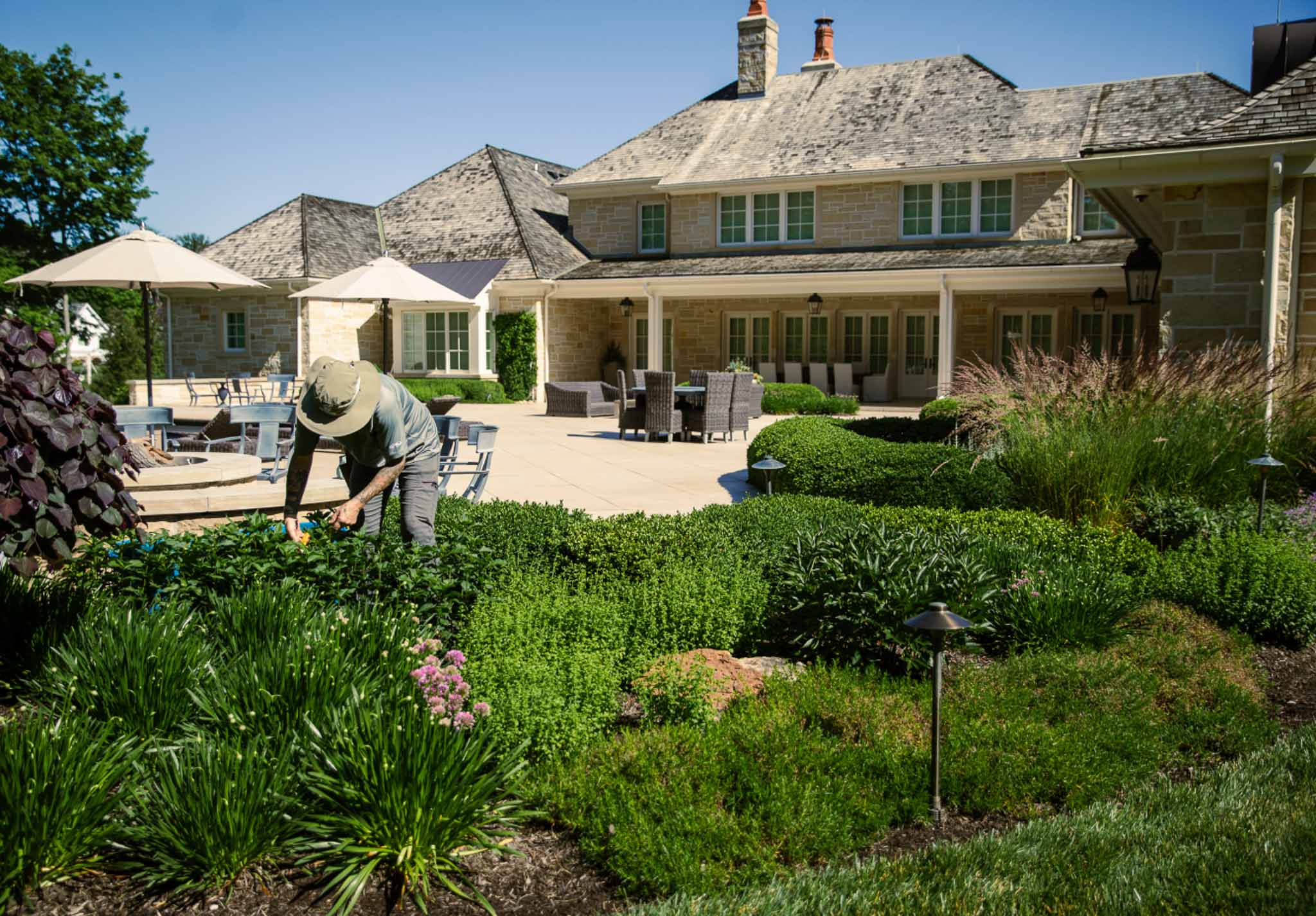 A landscaper working in a yard of a large house