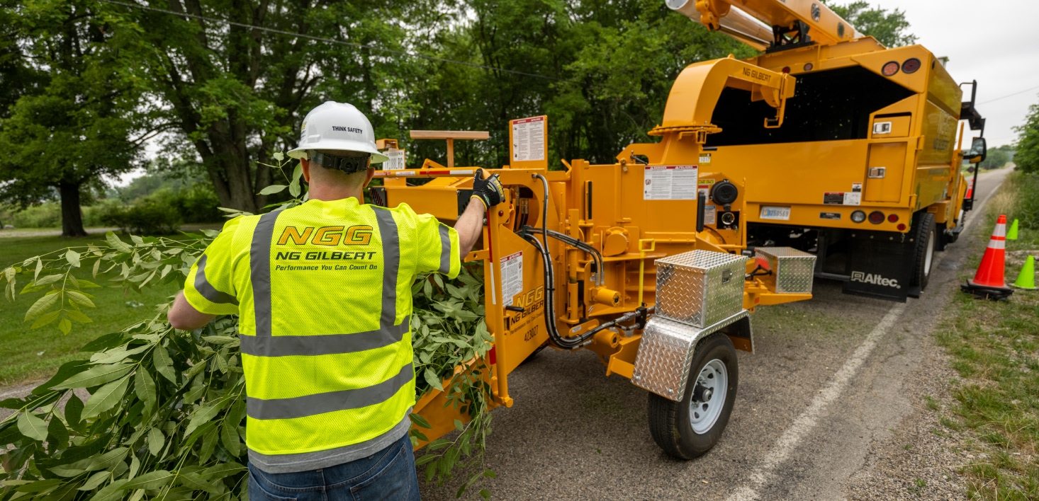 A worker feeding a branch into a wood chipper